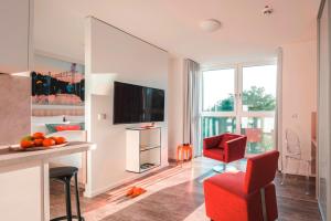 a living room with a red chair and a television at Mintrops Concierge Hotel in Essen