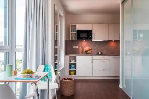 a kitchen with white cabinets and a table at Mintrops Concierge Hotel in Essen