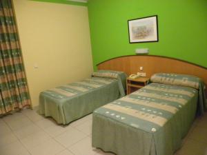 two beds in a room with green walls at Hostal Las Fuentes in Arévalo