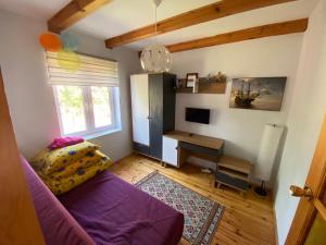 a living room with a purple couch and a desk at Dom pod Jabłonia in Stare Juchy