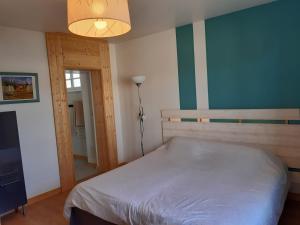 een slaapkamer met een wit bed en een lamp bij La maison bleue in Corpeau