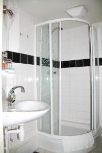 La salle de bains blanche est pourvue d'une douche et d'un lavabo. dans l'établissement 't Wapen van Middelie, à Middelie