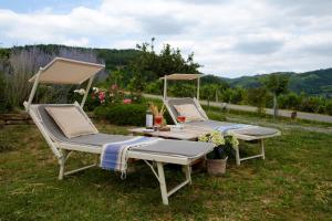 two lounge chairs and a table in the grass at Tre colline in langa in Bubbio