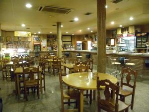 um restaurante com mesas e cadeiras de madeira e um bar em Hostal Las Fuentes em Arévalo