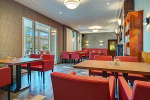 un restaurante con mesas y sillas rojas en Komforthotel Kaiserhof en Kelbra