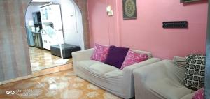 a living room with two chairs and a pink wall at Reeniy Homestay Mersing in Mersing