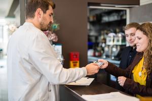 a man shaking the hand of a woman at a counter at Hôtel de la Tabletterie in Méru