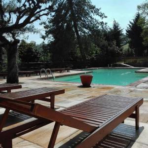 a wooden bench sitting in front of a swimming pool at Castello Rosso in Costigliole Saluzzo