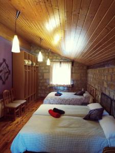 a bedroom with three beds and a stone wall at Hotel Rural del Médico in Regumiel de la Sierra