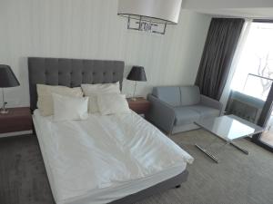 ein Schlafzimmer mit einem großen weißen Bett und einem Stuhl in der Unterkunft Apartament 514 Seaside z widokiem na morze in Kołobrzeg