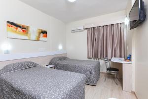 a hotel room with two beds and a table at Hotel Express Aeroporto in Porto Alegre