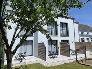 un edificio blanco con sillas y un árbol delante de él en Hotel au Moyne De Saire, en Réville