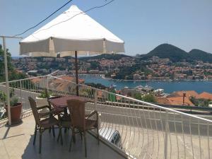 a table and chairs on a balcony with a white umbrella at Rooms Monika in Dubrovnik