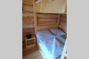 uma cama num quarto de madeira com um beliche em Hut at the forest em Male Brusnice