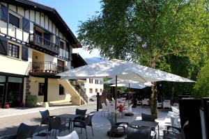 a patio with tables and chairs and an umbrella at Albergue "ARANTZAKO ATERPEA" in Arantza