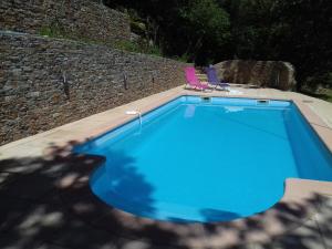una piscina blu con due sedie e un muro di Domaine de l'Insolite a Méounes-lès-Montrieux