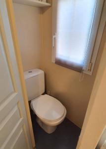 La salle de bains est pourvue de toilettes blanches et d'une fenêtre. dans l'établissement Mobil Home O'HARA Confort Plus Parc Saint James Montana, à Gassin
