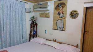 a bedroom with a bed and a picture of a woman at West Wind Homez - Home Stay in Cochin +26 photos