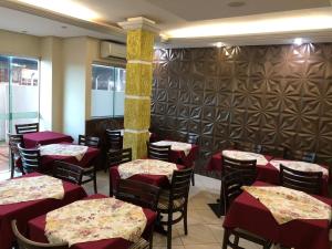 ein Esszimmer mit Tischen und Stühlen mit roten Tischdecken. in der Unterkunft Nioja Hotel in Itumbiara
