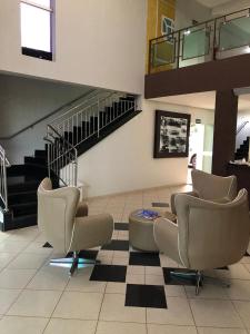 um átrio com cadeiras e uma escada num edifício em Nioja Hotel em Itumbiara
