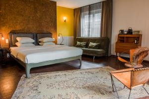 een slaapkamer met een bed en een bank bij Hotel V Nesplein in Amsterdam