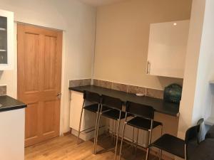 a kitchen with a counter and stools in a room at Jrs place in Merthyr Tydfil