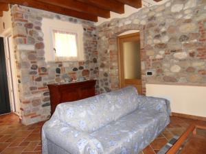 een woonkamer met een bank en een stenen muur bij Le Cocche in Affi