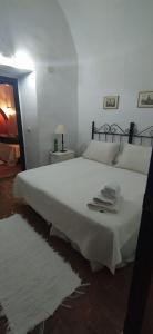 1 dormitorio con 1 cama blanca grande y toallas. en La Cartuja de Cazalla, en Cazalla de la Sierra