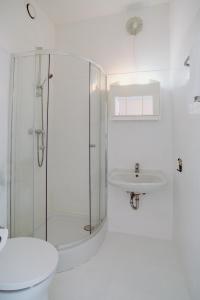 a white bathroom with a shower and a sink at Alper Hotel am Potsdamer Platz in Berlin