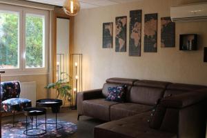 a living room with a brown couch and a window at The Originals City, Hôtel Rive Droite, Albi "Quartier Madeleine" in Albi