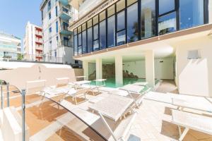 einen Balkon mit Stühlen und Tischen auf einem Gebäude in der Unterkunft Hotel Leon D'oro in Cattolica