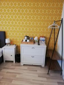 a bedroom with a white dresser and a yellow wall at 7th Room Guest House in Oświęcim