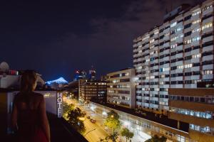 柏林的住宿－阿爾珀上午波茨坦廣場酒店，一位妇女晚上站在一座建筑物的顶端