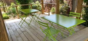 dwa zielone stoły i krzesła na drewnianym tarasie w obiekcie Villa Uhaïna Hossegor w mieście Soorts-Hossegor