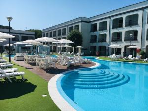 a swimming pool with chairs and umbrellas next to a building at Michelangelo Holiday & Family Resort in Lido di Spina