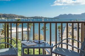 une table et des chaises sur un balcon avec vue sur la plage dans l'établissement Hotel Eolo, à Port de Pollença