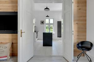 a kitchen with white walls and a door with a chair at Apartament Haffnera 30 in Sopot +59 photos