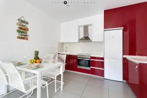 een keuken met een witte tafel en rode kasten bij Apartamento en la planta baja "Playa Elisa" in Pilar de la Horadada