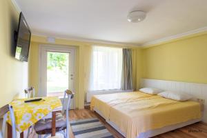 a yellow bedroom with a bed and a window at Zefír Apartments in Balatonfüred