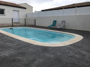 a swimming pool with two chairs next to a building at VILLA PINTOURINA in Sallèles-dʼAude