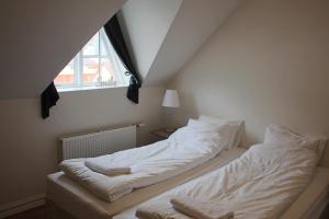 1 dormitorio con 1 cama con sábanas blancas y ventana en Mánagisting Guesthouse, en Ísafjörður