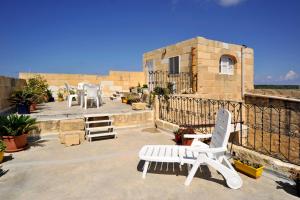 a patio with two white chairs and a table at Tal-Barun Farmhouse in San Lawrenz