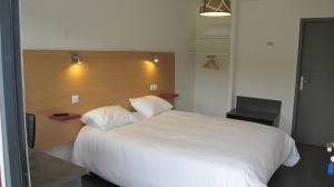 a bedroom with a large white bed with a wooden headboard at Hôtel Le 15 in Coulounieix-Chamiers