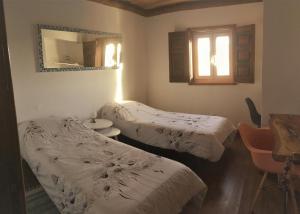 two beds in a room with a mirror at Portela Guesthouse in Cercal