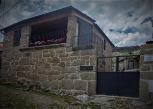 een stenen huis met een poort en bloemen erop bij Beirais do Alvão in Vila Real