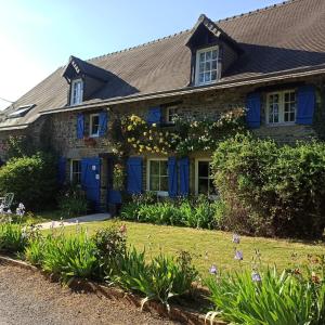 een huis met blauwe deuren en bloemen in de tuin bij Belle Longère in Campeaux