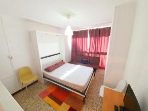 um pequeno quarto com uma cama e uma cadeira amarela em Estudio Karina Beach-4 em Empuriabrava