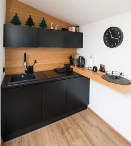eine Küche mit schwarzen Schränken und einer Uhr an der Wand in der Unterkunft Minimal House in Szczyrk