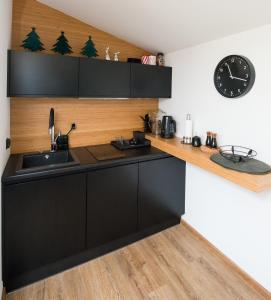 a kitchen with black cabinets and a clock on the wall at Minimal House in Szczyrk
