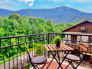 balcone con tavolo e sedie in legno e montagne di SUITE ROMANTICA - Vista Montagna a Rubiana